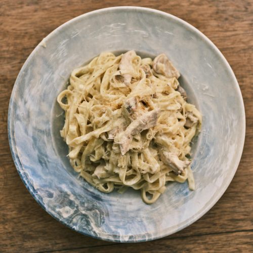 A delicious homemade fettuccine Alfredo pasta dish served on a rustic wooden table.